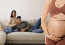 Pregnant woman holding her belly in a living room