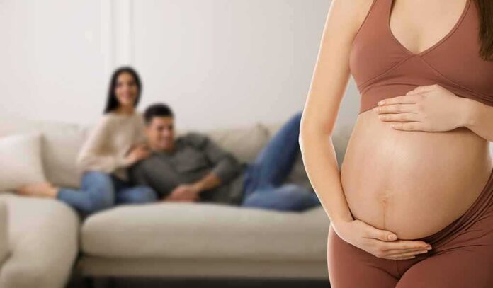 shutterstock_2150484801 Pregnant woman holding her belly in a living room
