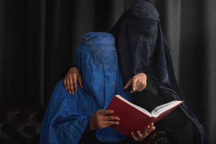 Two veiled women reading a red book together
