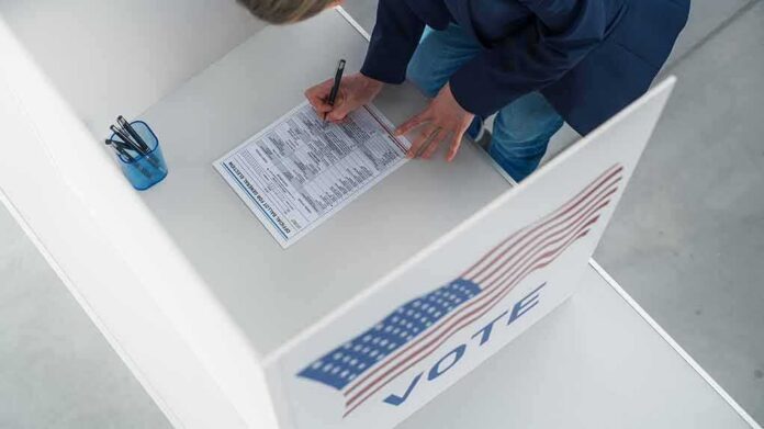 shutterstock_2420116561 Voter filling out a ballot in a private voting booth