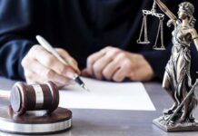 Money Trail Topples $20M Migrant Pipeline Judge writing at desk with gavel and Lady Justice statue