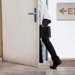 Gabbard’s Departure Sparks Intelligence Leadership Crisis person with briefcase exiting through a door