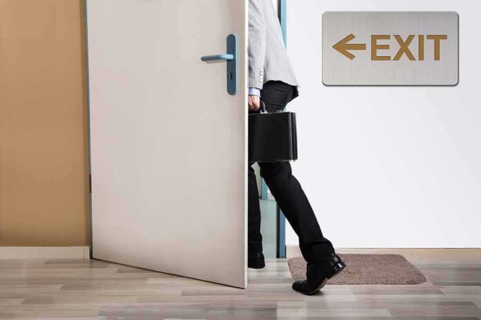 person with briefcase exiting through a door