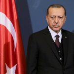 NATO Showdown: Israel Taunts Erdoğan man in suit standing beside Turkish flag