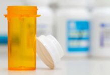 Empty orange prescription bottle with white cap