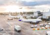 Airport Breach Sparks Ground Shutdown Airplanes at airport gates during sunset with ground vehicles and jet bridges