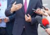 Businessperson in suit speaking to reporters with microphones
