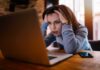 Championship Hype Turned Corporate Trap – Workers Outraged Woman holding her head while looking at a laptop