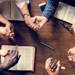 Christian Ministries Muzzled – Unequal Rules Exposed Group holding hands around open books on a wooden table