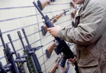 DOJ Backs Off – NFA Power Evaporates Person examining a black rifle in a gun store