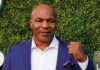 Mike Tyson in a blue suit raising a fist