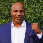 Mike Tyson in a blue suit raising a fist