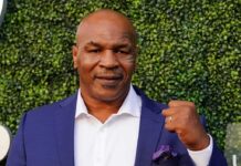 Mike Tyson in a blue suit raising a fist