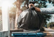 City Cleans House – Nightmare Crawls Back Hand dropping a black garbage bag into a blue bin