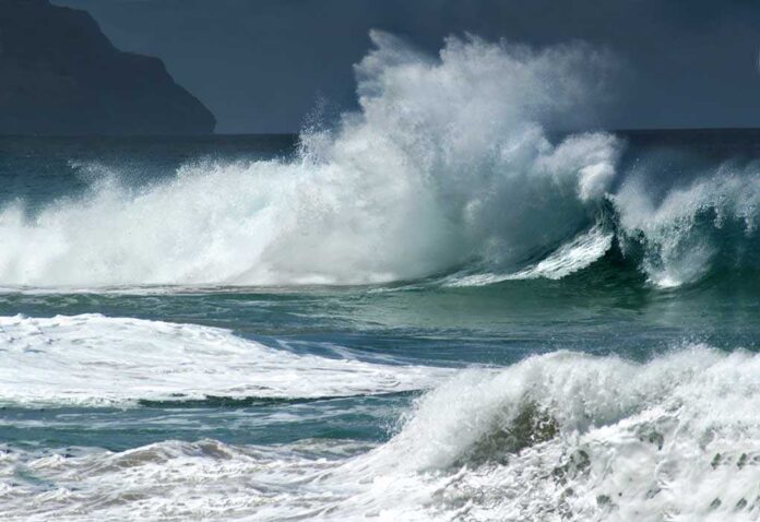 Crashing ocean waves against the shore under a cloudy sky