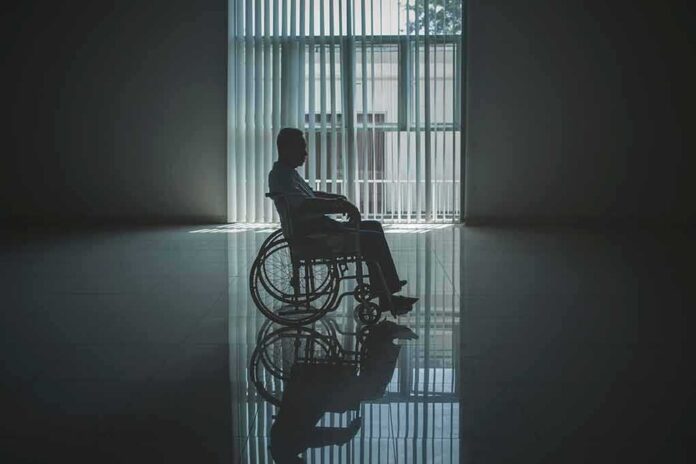 shutterstock_1402442765 Person in a wheelchair silhouetted by a large window