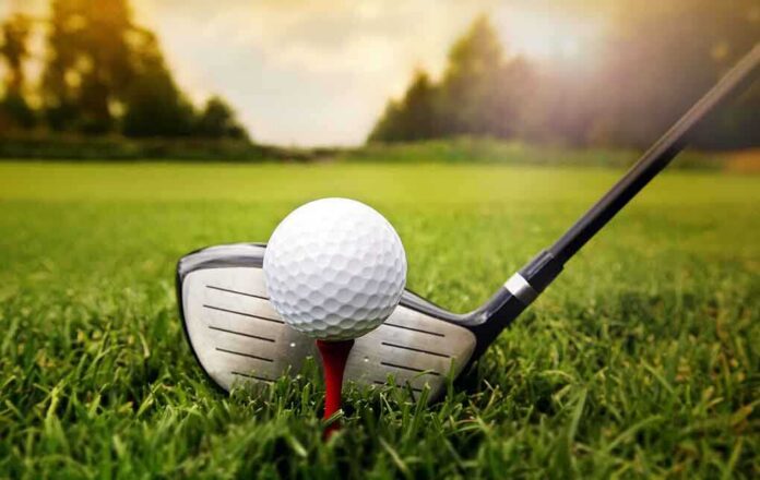 shutterstock_158881226 A golf ball on a tee with a golf club resting beside it on green grass