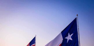 Texas and United States flags waving at sunset