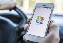 A person holding a smartphone displaying the Google Maps app while driving