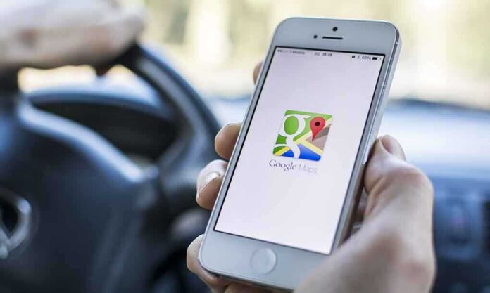 shutterstock_176093684 A person holding a smartphone displaying the Google Maps app while driving