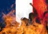 silhouetted crowd and flames before a French flag