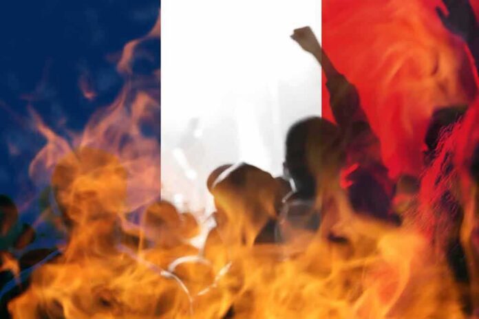 silhouetted crowd and flames before a French flag