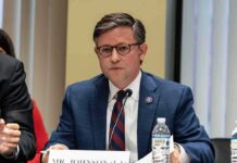 GOP Revolts Over ‘Execution TV’ A public official speaking at a meeting with a nameplate in front of him