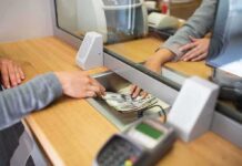 Bank teller hands cash to customer through security window