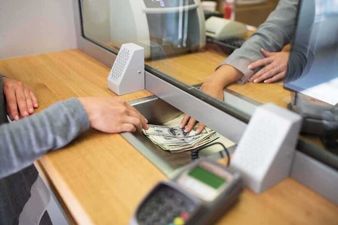 Bank teller hands cash to customer through security window