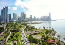 7.7 Monster Hits – Panama On Edge Coastal city skyline with waterfront park and busy boulevard